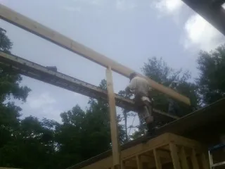 Carpenter setting a ridge beam over a new addition frame — Ice Dam Removal by Roofing Brothers in Elk Park