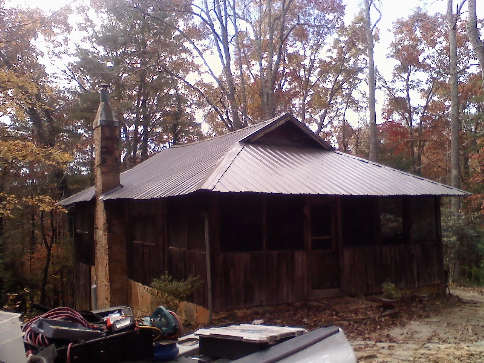 Brown metal hip roof on an old cabin with a stone chimney in Elk Park