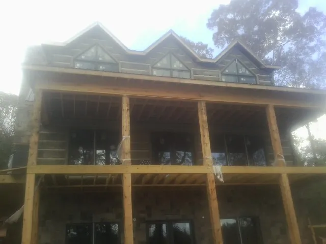 Dormers and porch framing on a large log home under construction — Roof Coating work by our crew in Elk Park