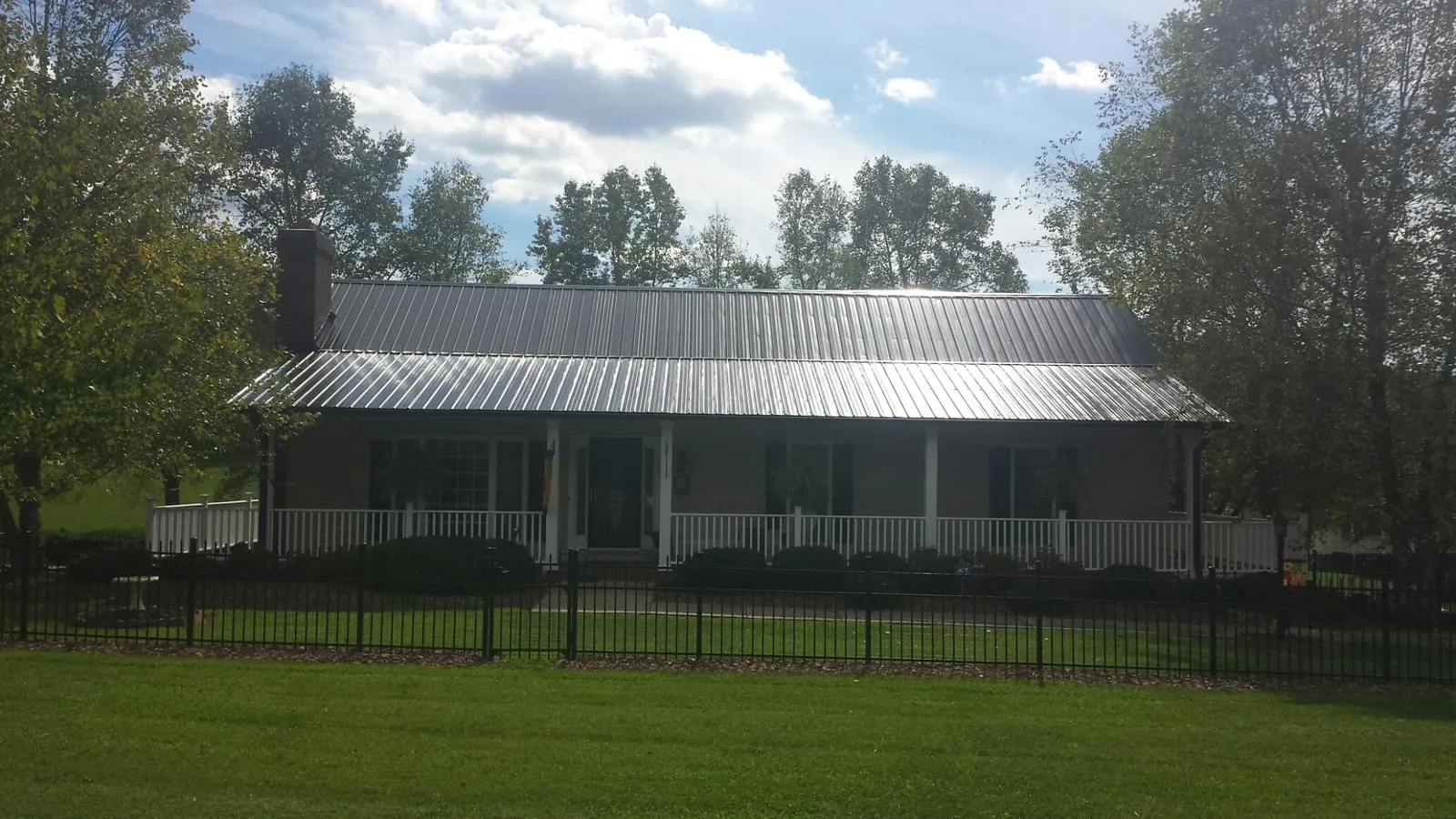Gray metal roof on a brick ranch with a full width front porch — Gutter Guard Installation work by our crew in Elk Park