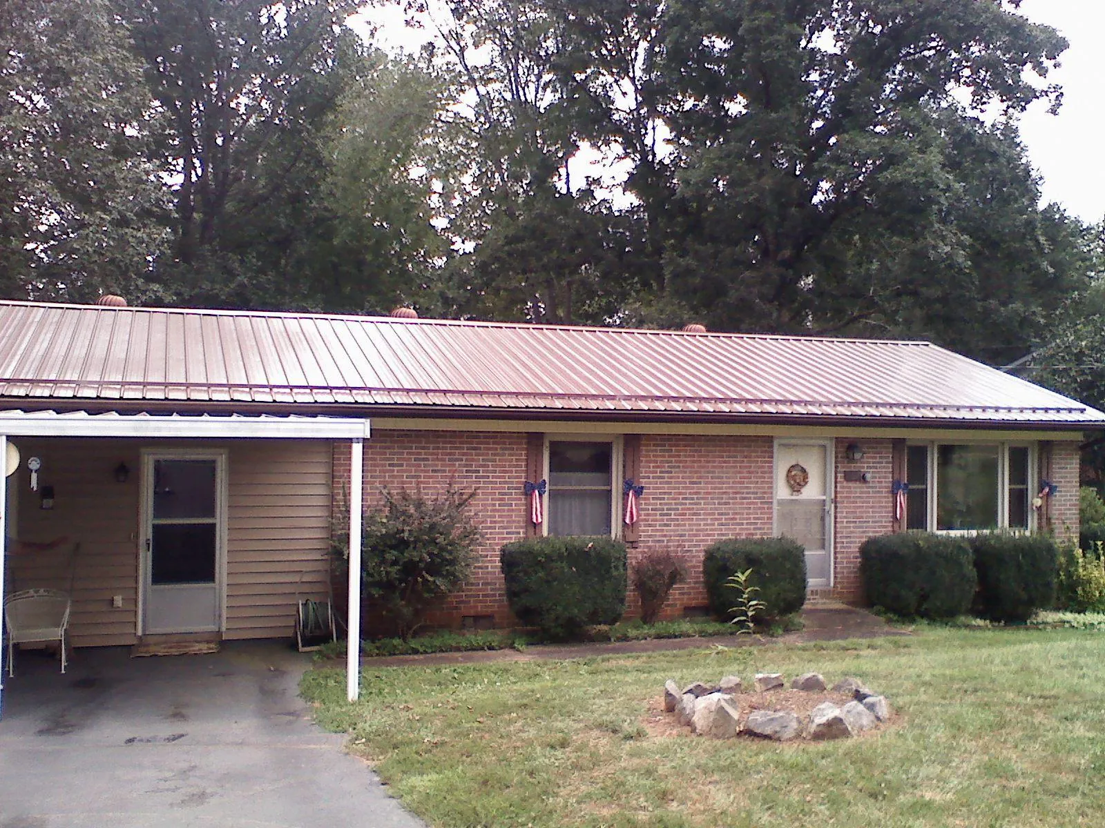 Bronze metal roof and carport on a brick ranch home — Roof Repair work by our crew in Elk Park