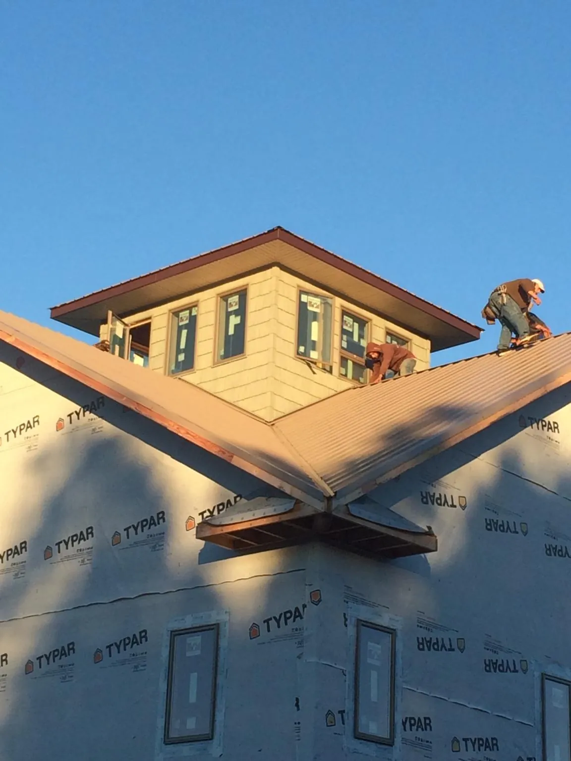 Roofers working around a rooftop cupola on a new metal roof at sunset — Roof Waterproofing in Elk Park by Roofing Brothers